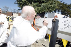 Fr. Brian Shanley signs a beam at the Ryan Center Topping Off Ceremony.