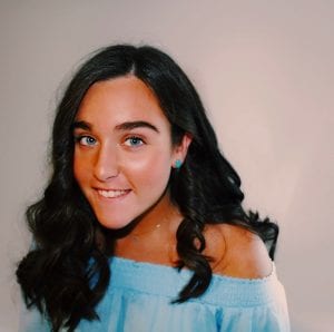 woman in blue shirt smiling at the camera