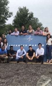 a group of 14 interns gathered around a blue Lockheed Martin sign