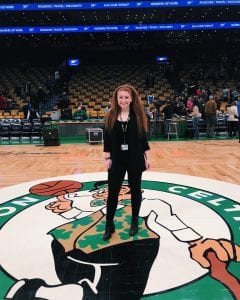 girl in black clothing with long red hair standing center court where the Boston Celtics play
