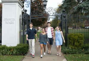 four students walking under an iron wrought gate