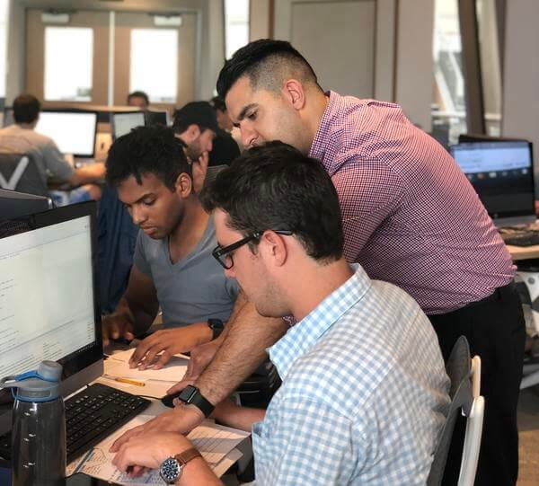 Professor working with two male students at computer terminals