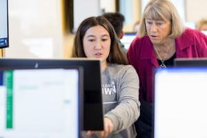 Professor Faith Lamprey helps a female student at a computer.