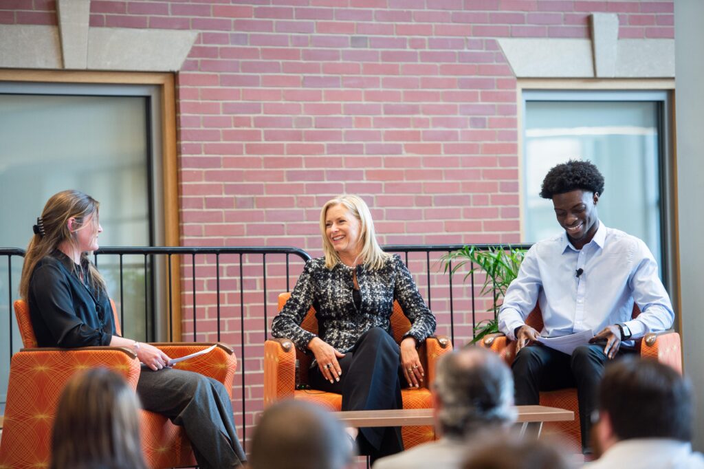 Student moderators Anna LaFortune '22 and Joseph Adegboyega ’22 sit on the stage at the PCSB Dean's Symposium with keynote speaker Kelly Grier of EY.