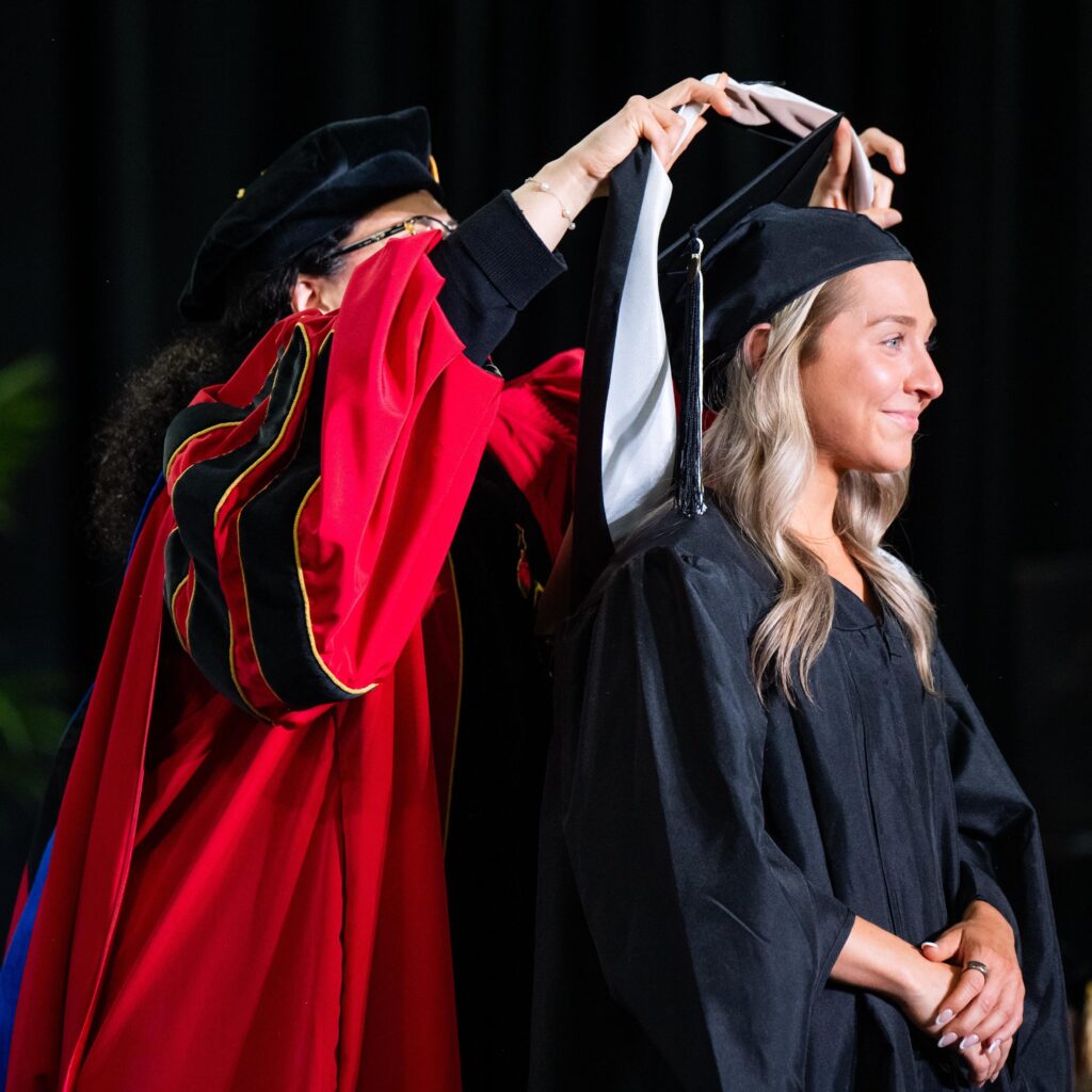 A MBA graduate receives her master's degree hood at commencement.