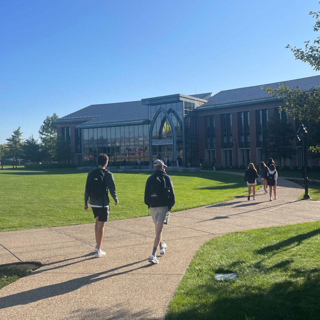 Students walk toward the Ryan Center for Business Studies on a sunny day.