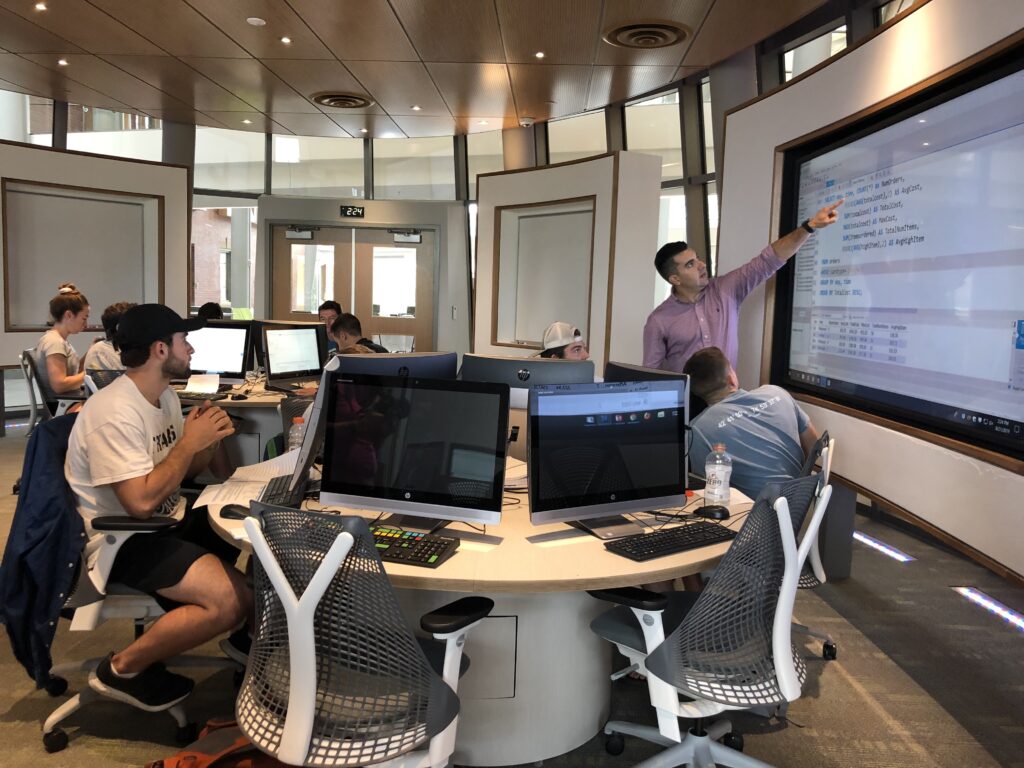 Professor teaching students pointing to a screen