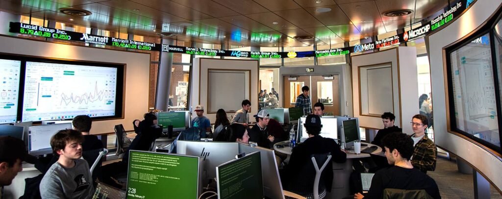 Students working in the finance lab with the stock ticker in the background