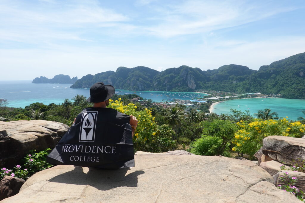 Student with Providence College Flag overlooking water